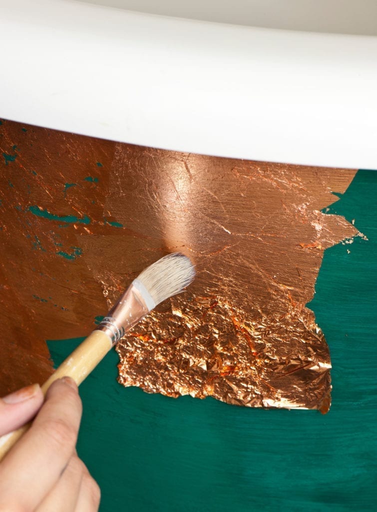 Aplicación de pan de metal suelto en cobre sobre una bañera pintada con Chalk Paint™ en tono Florence