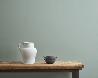Pared pintada en Upstate Blue con Wall Paint de Annie Sloan, junto a una maceta blanca y negra

