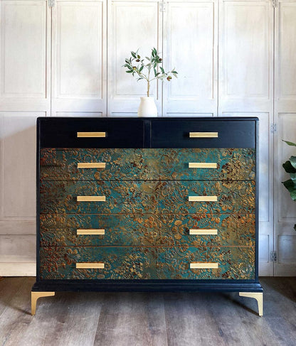 Papel decoupage fibra Pátina Envejecida de Re-Design with Prima aplicado en cómoda negra con tiradores dorados — motivos barrocos en azul turquesa y cobre, estilo lujoso contemporáneo

