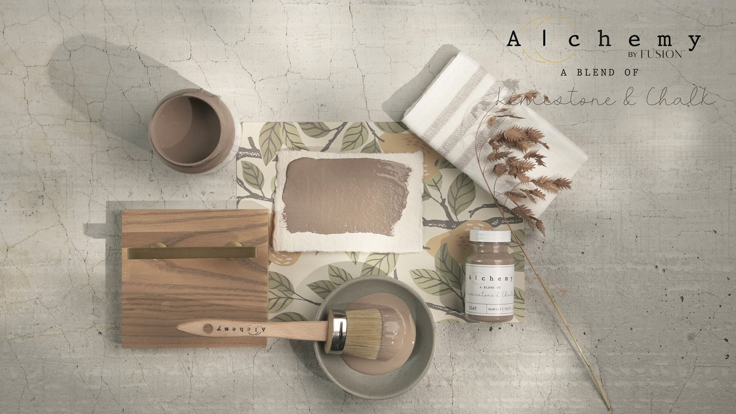 Flatlay inspiracional Alchemy by Fusion Clay con muestra de color, brocha redonda, bote 120ml y elementos naturales sobre fondo de azulejo craquelado