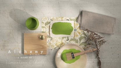 Flatlay inspiracional Alchemy by Fusion Moss con muestra de color chartreuse, bote 120ml, brocha, tirador de madera y elementos naturales sobre fondo de azulejo craquelado