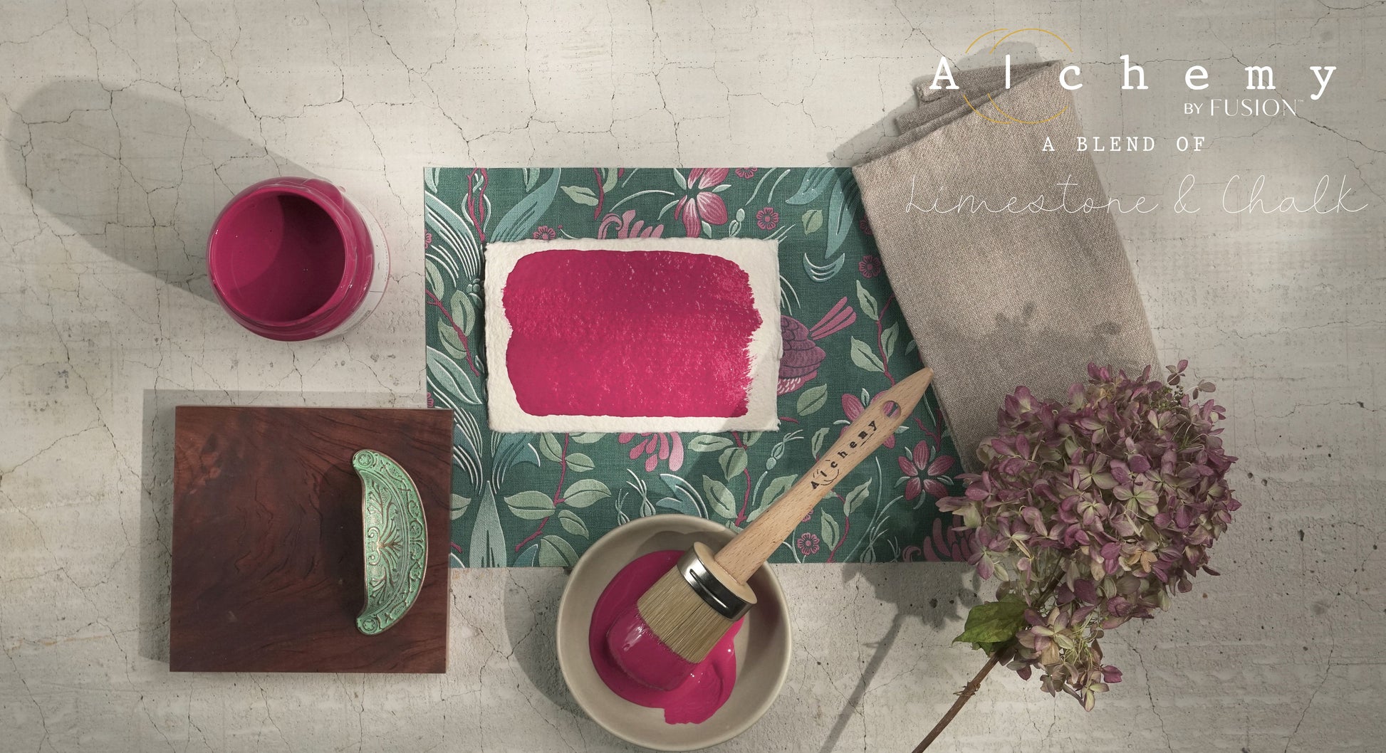 Flatlay inspiracional Alchemy by Fusion Raspberry con muestra de color fucsia, bote 120ml abierto, brocha redonda, tirador cerámico verde y hortensia seca sobre fondo de azulejo craquelado