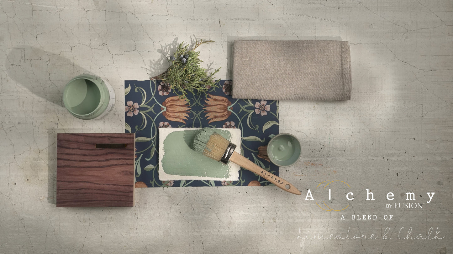 Flatlay inspiracional Alchemy by Fusion Thyme con muestra de color verde azulado, bote 120ml, brocha redonda, papel botánico azul y rama de romero fresco sobre fondo de azulejo craquelado