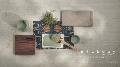 Flatlay inspiracional Alchemy by Fusion Thyme con muestra de color verde azulado, bote 120ml, brocha redonda, papel botánico azul y rama de romero fresco sobre fondo de azulejo craquelado