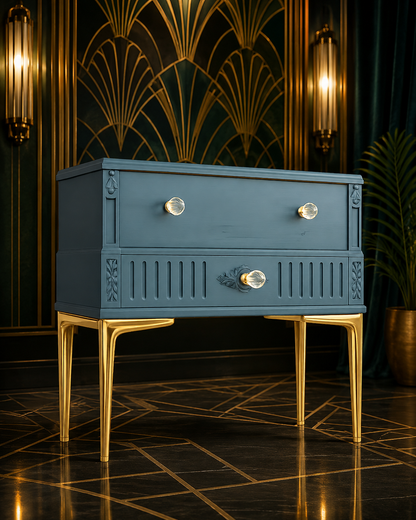 Detalle frontal de mesita de noche Art Déco azul restaurada a mano, con tiradores de cristal y relieves tallados en madera, patas metálicas doradas