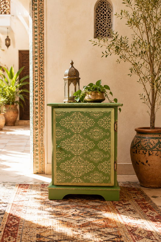 Mueble auxiliar verde oliva con motivo ornamental dorado pintado a mano, estilo marroquí, en patio mediterráneo — Anaqa Design