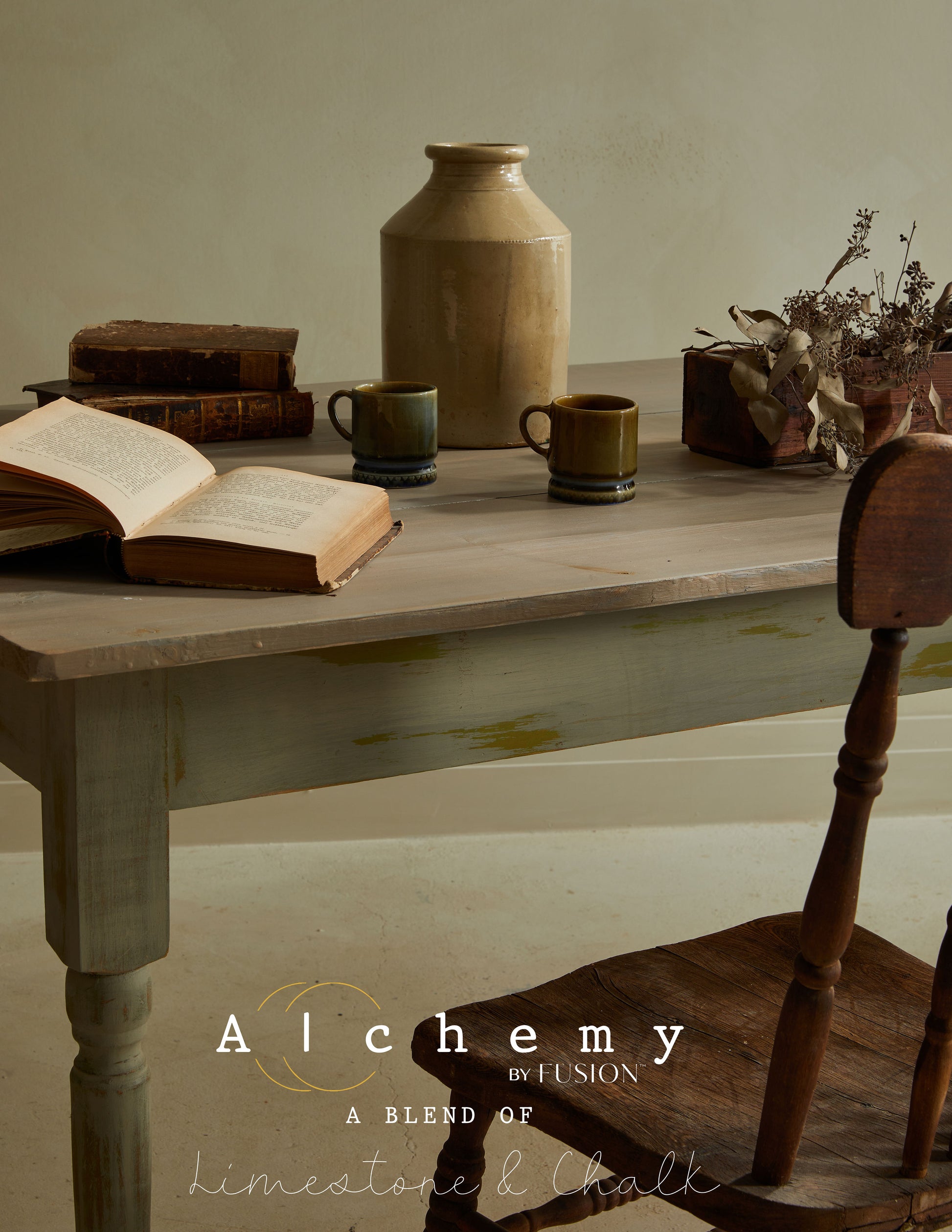 Detalle de mesa vintage restaurada con Alchemy by Fusion Sage en verde salvia con efecto envejecido, decorada con libros, jarra cerámica y tazas artesanales, pintura limestone y chalk