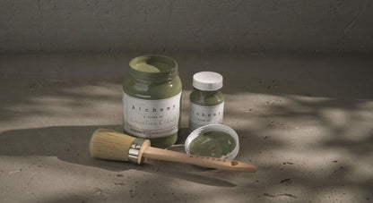 Botes Alchemy by Fusion Rosemary 500ml y 120ml abiertos con brocha redonda sobre superficie de cemento con sombras de luz natural, pintura a la tiza verde medio herbáceo
