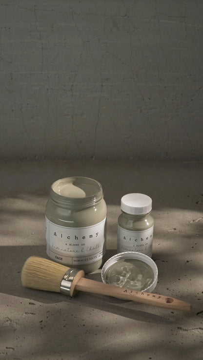 Botes Alchemy by Fusion Sage 500ml y 120ml con brocha sobre fondo de cemento texturizado, pintura a la tiza verde salvia limestone y chalk