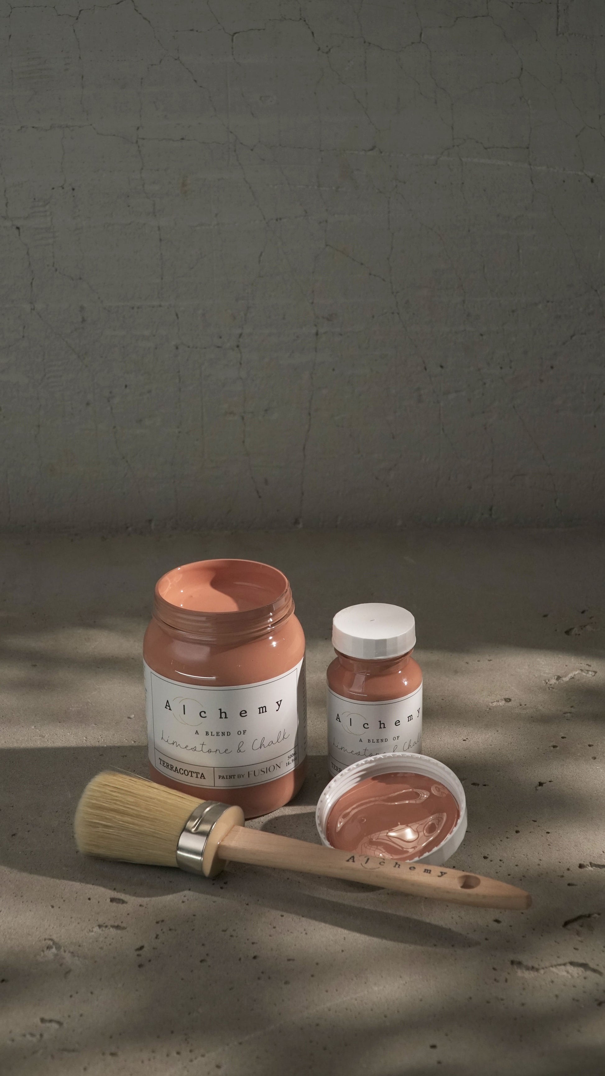 Botes Alchemy by Fusion Terracotta 500ml y 120ml con brocha sobre fondo de cemento texturizado, pintura a la tiza terracota limestone y chalk