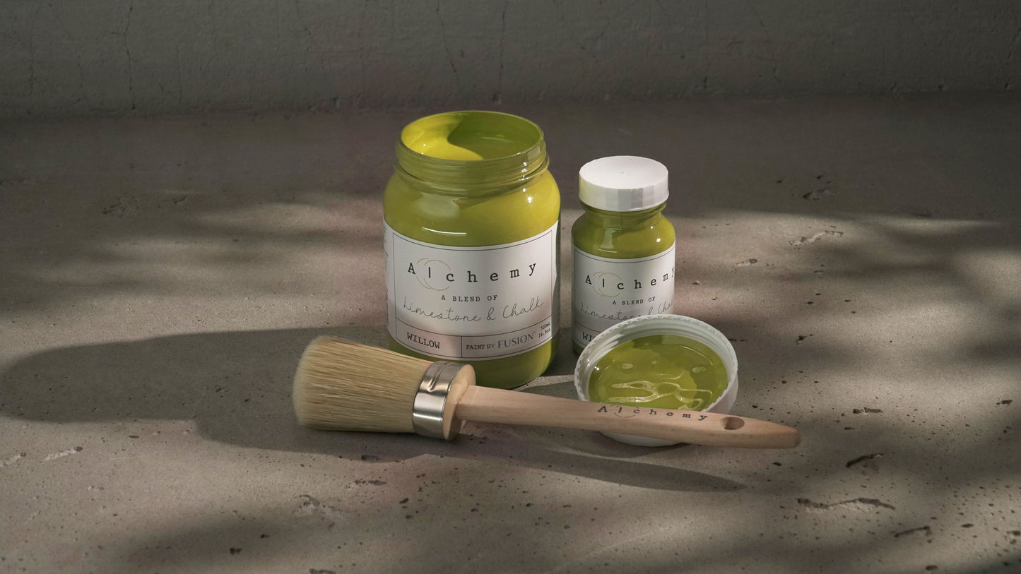 Botes Alchemy by Fusion Willow 500ml y 120ml abiertos con brocha redonda y tapa sobre superficie de cemento con sombras de luz filtrada, pintura a la tiza mostaza y chartreuse