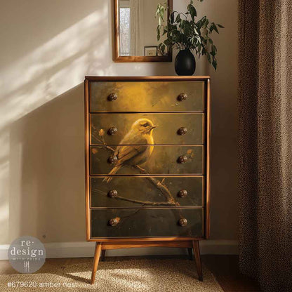 Papel decoupage Amber Nest Kacha aplicado en cómoda alta mid-century madera natural con tiradores dorados - pájaro dorado sobre fondo ámbar oscuro en cajones - Re-Design with Prima
