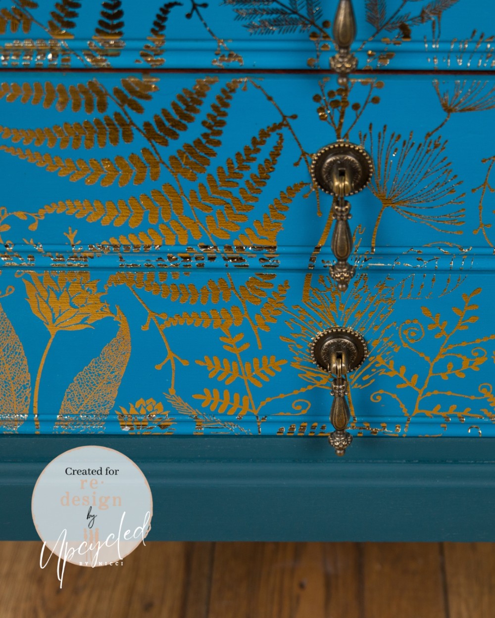Detalle de transferencia decorativa Foliage Finesse Kacha en cajones azul turquesa - helechos y follaje botánico dorado con tiradores de bronce - Re-Design with Prima
