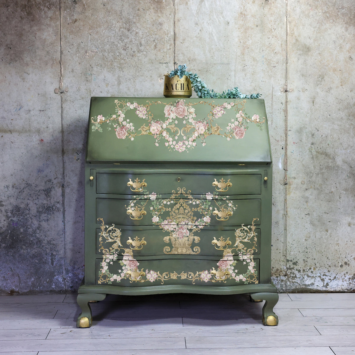 Transferencia decorativa Petit à Petit Kacha en cómoda negra con detalles dorados restaurada - arabescos florales dorados y texto Petit à Petit L'Oiseau Fait Son Nid en cajones - Re-Design with Prima
