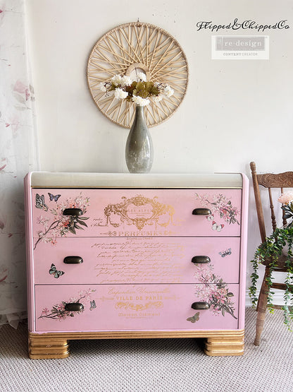 Transferencia decorativa Gold Foil Perfume Notes Kacha en cómoda rosa palo art déco restaurada - texto dorado Perfumes Ville de Paris con mariposas y flores en cajones, tiradores negros - Re-Design with Prima - ambassador Flipped and Chipped Co

