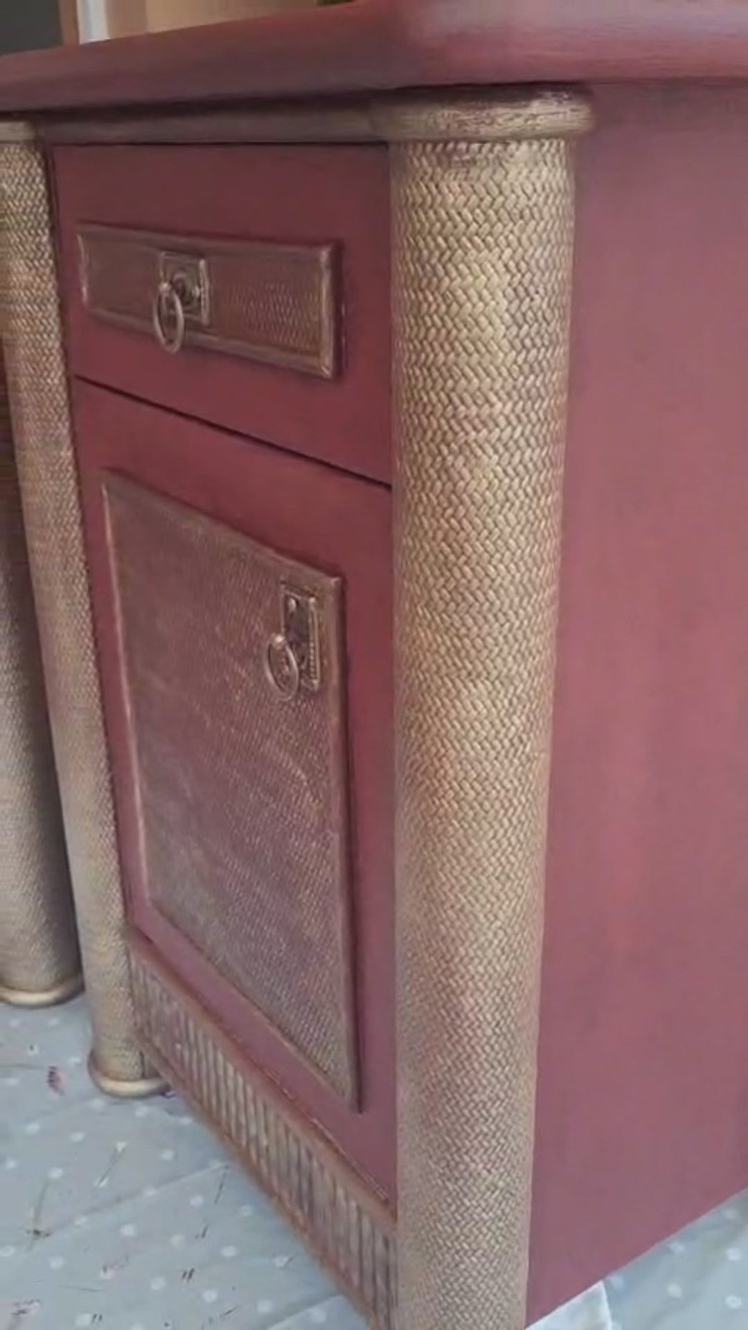 Mesita de noche vintage restaurada en burdeos y dorado envejecido, con columnas texturizadas, cajón y puerta con tiradores de anilla.